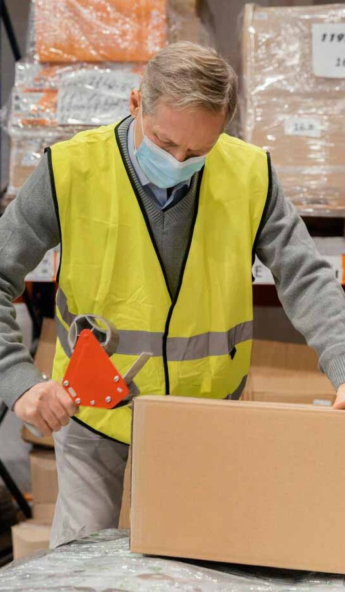 Pakowanie kartonów w magazynie – zabezpieczanie ładunków taśmą pakującą w transporcie logistycznym.